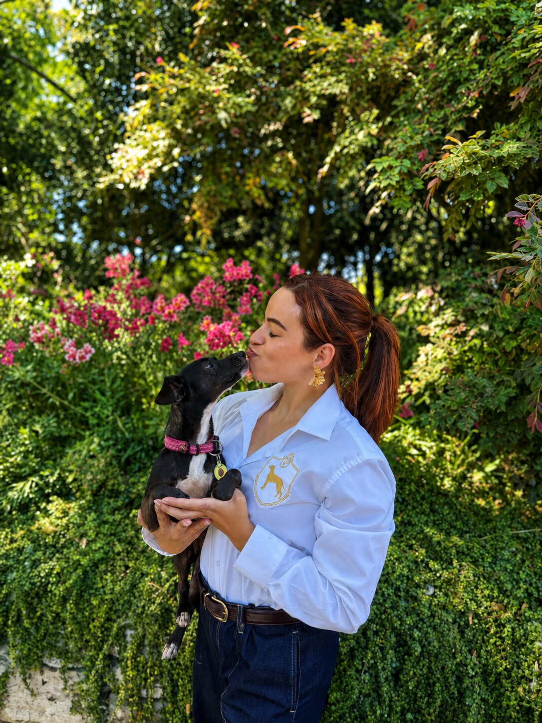 Gisela Castro, founder of The Vow Companion, holding a dog in a garden